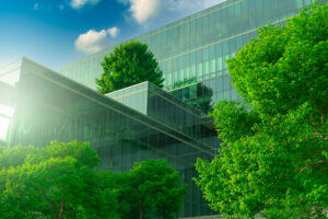 Eco-friendly building with vertical garden in modern city. Green tree forest on sustainable glass building. Energy-saving architecture with vertical garden. Office building with green environment.